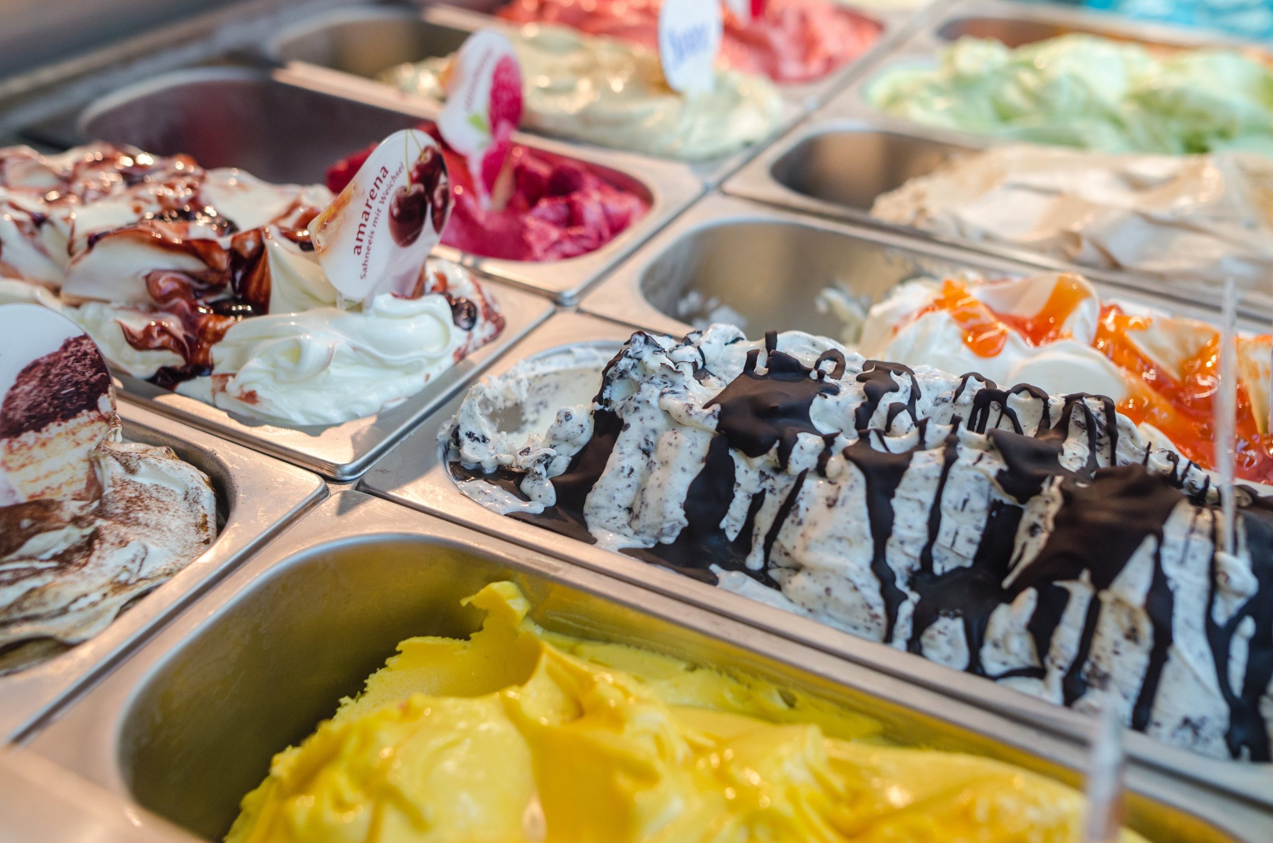 Mehrere bunte Eissorten bei der Theke einer Eisdiele.