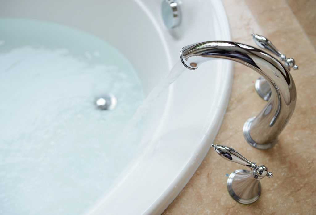 Ein laufender Wasserhahn füllt Wasser in eine Badewanne.