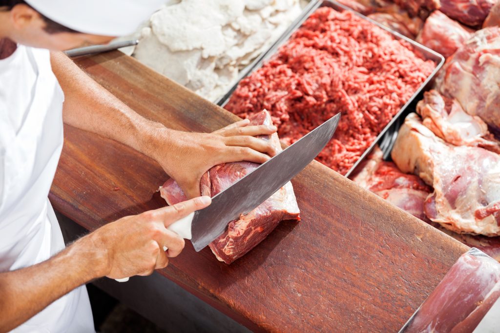 Ein Metzger schneidet Fleisch auf einer Theke.
